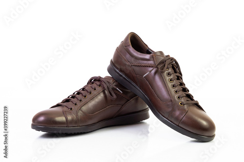 Pair of unbranded brown genuine leather shoes isolated on white reflective surface, closeup