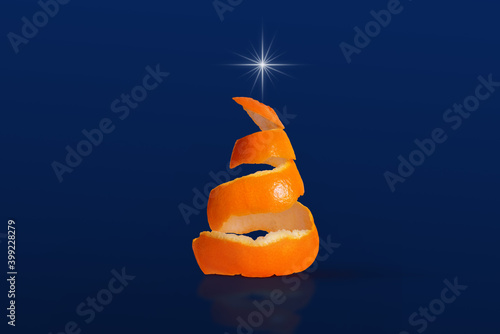 Spiral cut orange fruit that simulates the shape of a Christmas tree on blue background