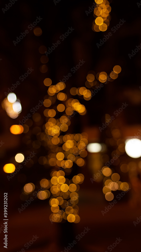 Abstract evening night shimmering bokeh background effect street outside near cafe restaurant. Defocused urban city life blur golden light bulbs garlands. Christmas New Year party holiday concept. 
