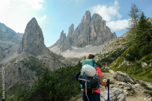 Valokuva A woman with big backpack and sticks, hiking in high Italian Dolomites