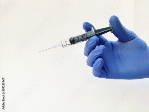 Foto Syringe in hand wearing gloves on white background
