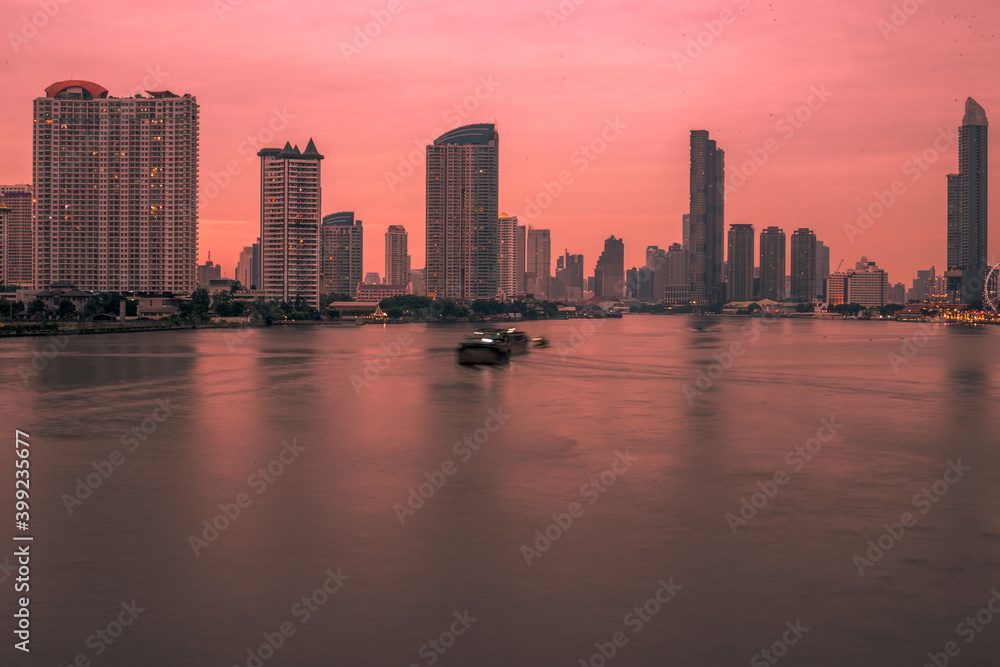 Fototapeta premium Blurred abstract background of high-rise buildings built by the river, lit at night, the distribution of residences of today's capital so