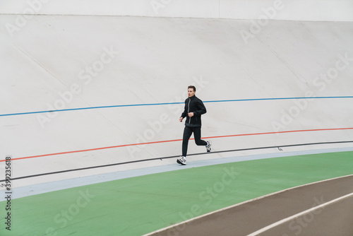 Young sporty man running at the stadium