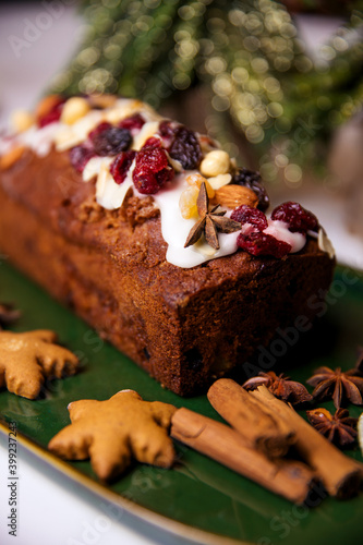 Christmas poppy seed cake covered with icing and decorated with raisins and walnuts on the holiday table.