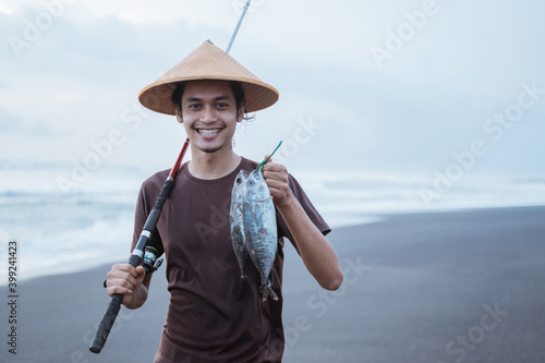 Close up young fisherman showing his captured fish on the beach
