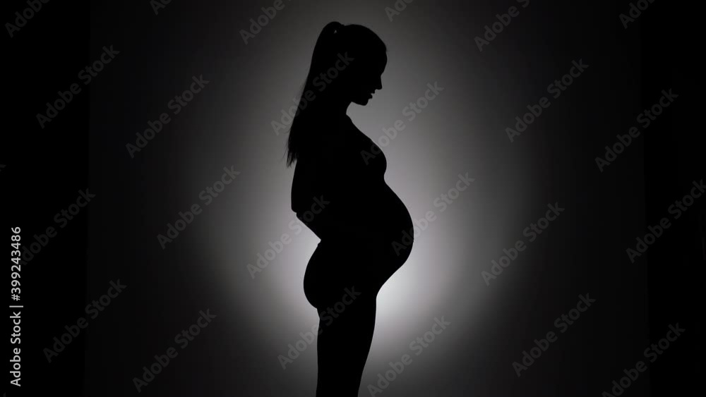 a silhouette of a pregnant woman entering the frame ,caressing her belly and talk a silhouette of a pregnant woman entering the frame ,caressing her belly and talk