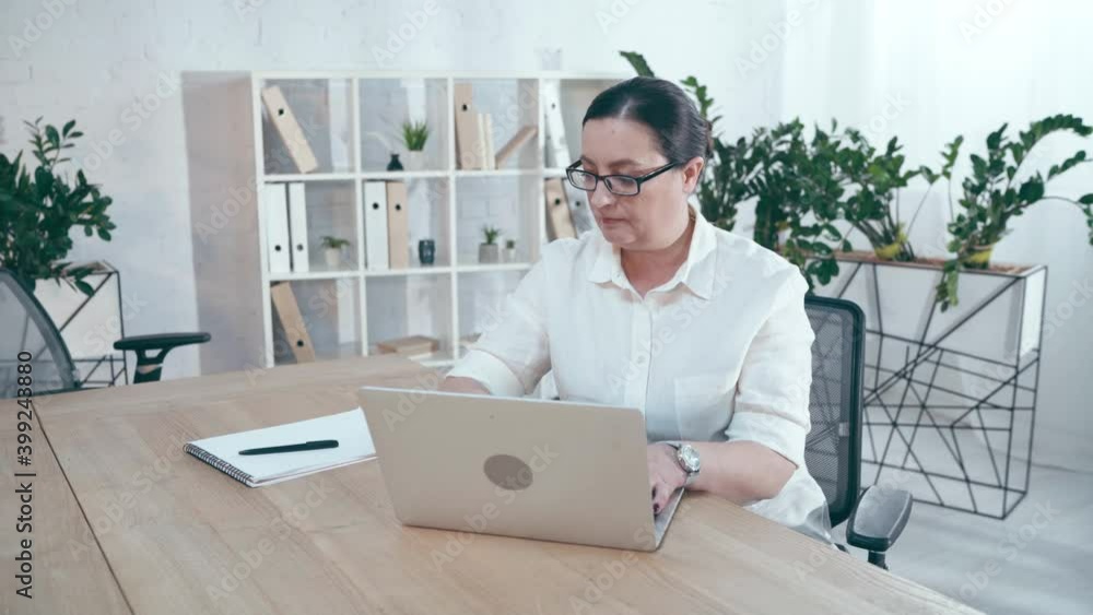 hispanic businesswoman typing on laptop and writing in notebook in office hispanic businesswoman typing on laptop and writing in notebook in office