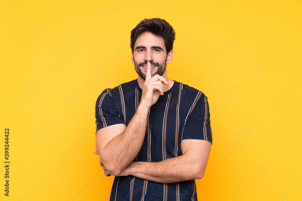 Young handsome man with beard over isolated yellow background doing silence gesture Young handsome man with beard over isolated yellow background doing silence gesture