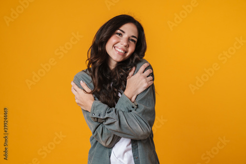 Lovely smiling woman embracing herself isolated