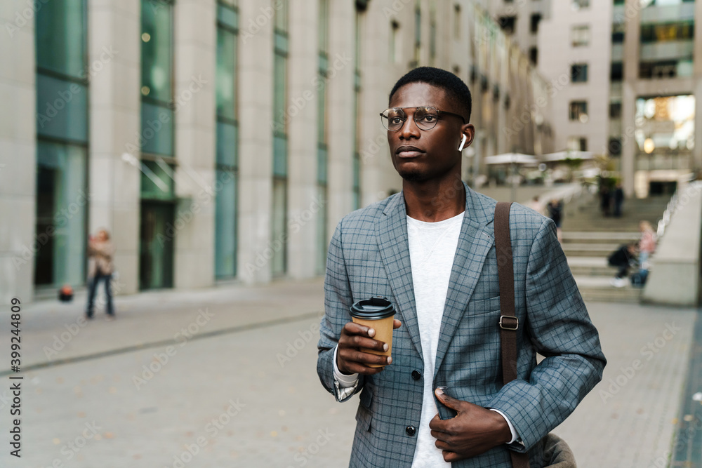 Attractive young african businessman in wireless earphones Attractive young african businessman in wireless earphones