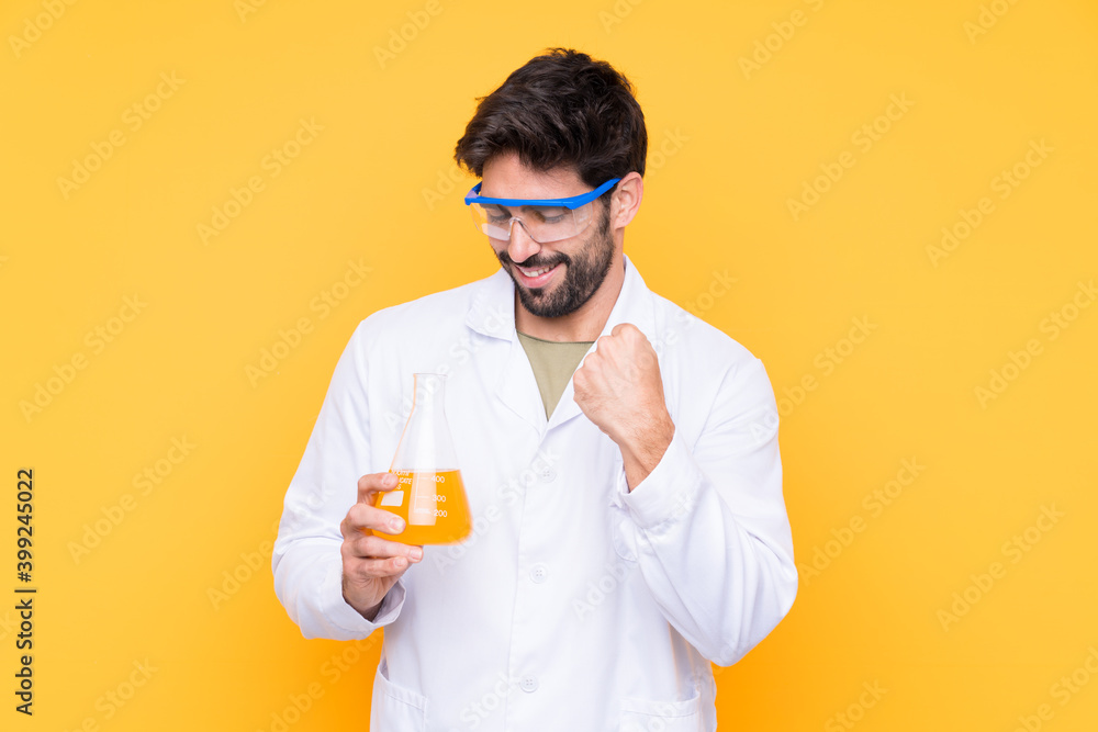 Young scientific man over isolated yellow background celebrating a victory Young scientific man over isolated yellow background celebrating a victory