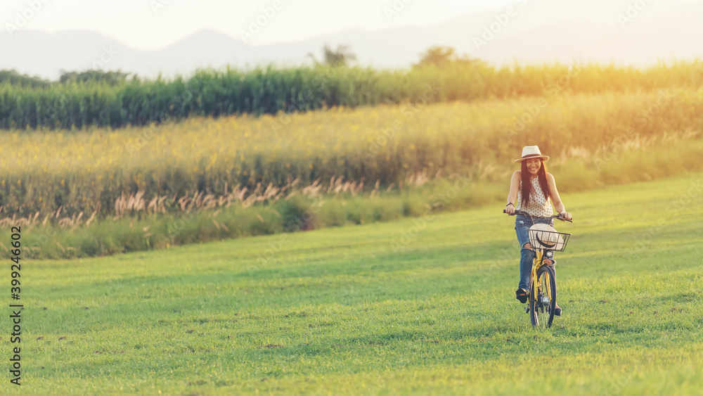 Lifestyle woman with bicycling at the garden meadow in sunset near mountain background. Lifestyle Concept Lifestyle woman with bicycling at the garden meadow in sunset near mountain background. Lifestyle Concept