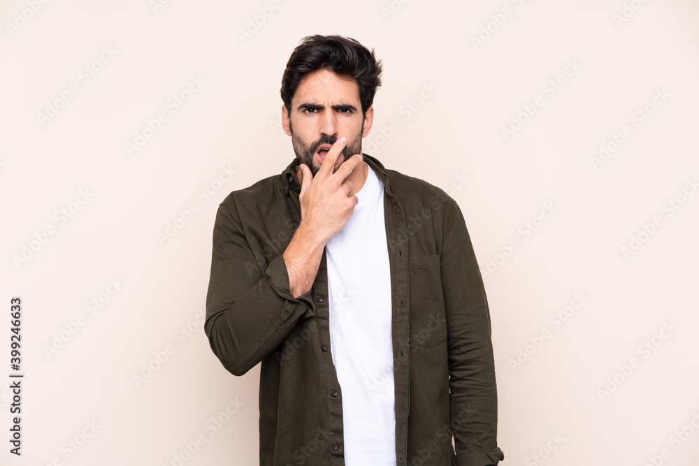 Young handsome man with beard over isolated background surprised and shocked while looking right Young handsome man with beard over isolated background surprised and shocked while looking right