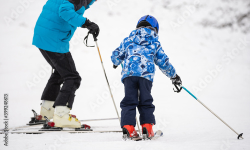 Professional ski instructor is teaching a child to ski on a day on a mountain slope resort with snow. Family and children active vacation.