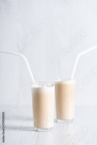 Trendy breakfast. Dalgon coffee. Milkshake with instant coffee and sugar, whipped to a thick foam in glasses with a straw on a light background.