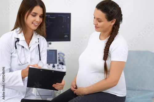 Pregnant lady talking with doctor during regular examination