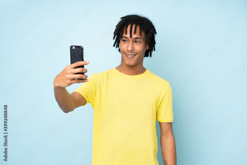 Young african american man isolated on blue background making a selfie Young african american man isolated on blue background making a selfie