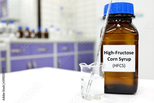 Selective focus of high-fructose corn syrup or hfcs food and beverage sweetener in dark brown glass bottle inside a laboratory. photo