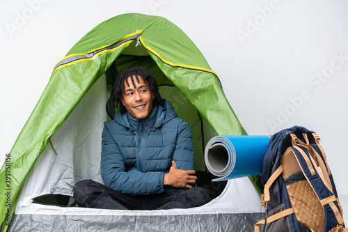 Young african american man inside a camping green tent with arms crossed and happy