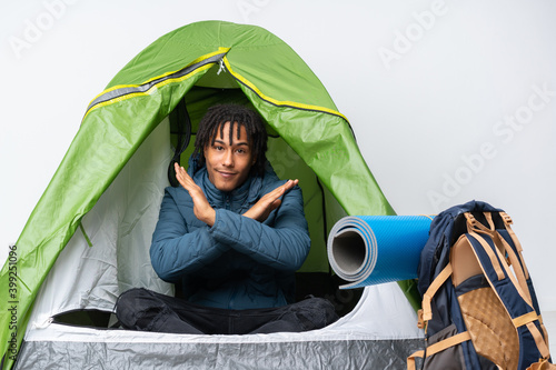 Young african american man inside a camping green tent making NO gesture