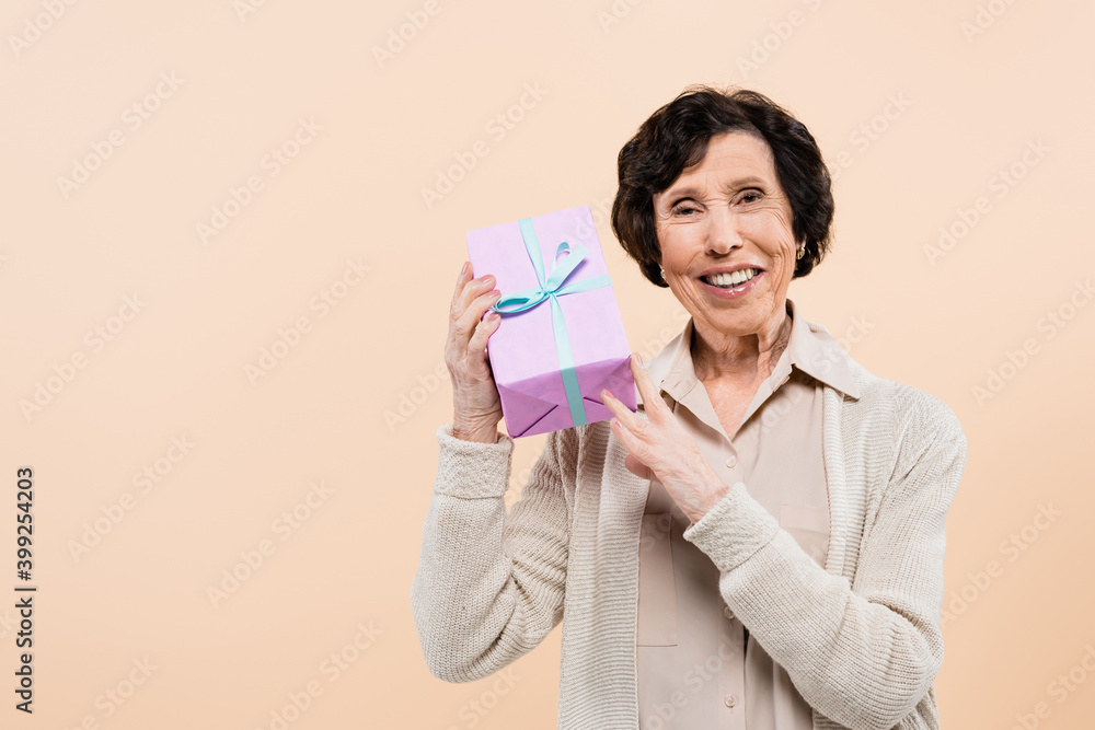 Cheerful hispanic woman holding present isolated on beige Cheerful hispanic woman holding present isolated on beige