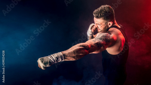 Sportsman muay thai boxer fighting on black background with smoke. Sport concept.