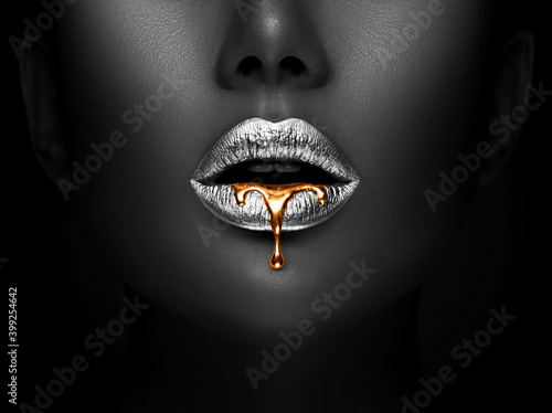 Golden lipstick closeup. Liquid metal dripping from silver lips. Beautiful makeup. Sexy lips, bright liquid paint on beauty model girl's mouth, close-up. Lipstick. © Subbotina Anna