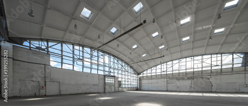 Corner of huge empty industrial warehouse. White interior. Hemispherical reinforced concrete load bearing roof. Metal construction. Unique architecture.