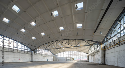 Huge empty industrial warehouse. White interior. Unique architecture. Hemispherical reinforced concrete load bearing roof with windows. Modern building.