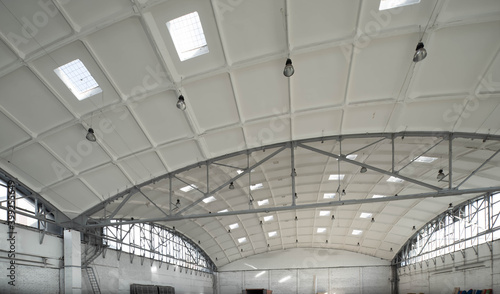 Hemispherical reinforced concrete load bearing roof with windows in huge industrial warehouse. White interior. Unique soviet architecture.