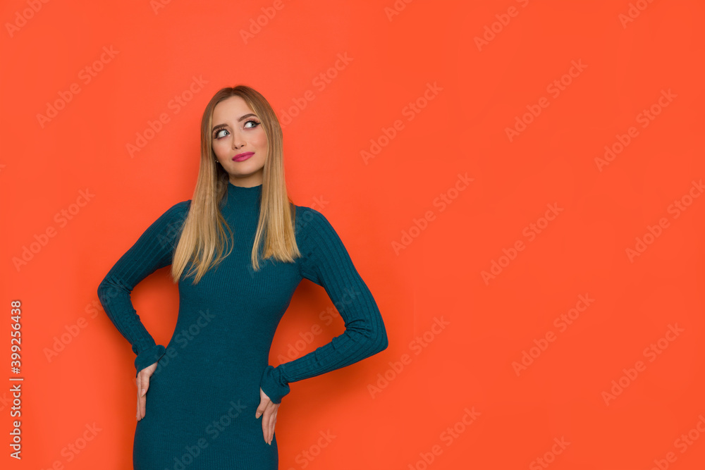 Beautiful Young Woman In Teal Fitted Dress Is Holding Hands On Hip And Looking At The Side Beautiful Young Woman In Teal Fitted Dress Is Holding Hands On Hip And Looking At The Side