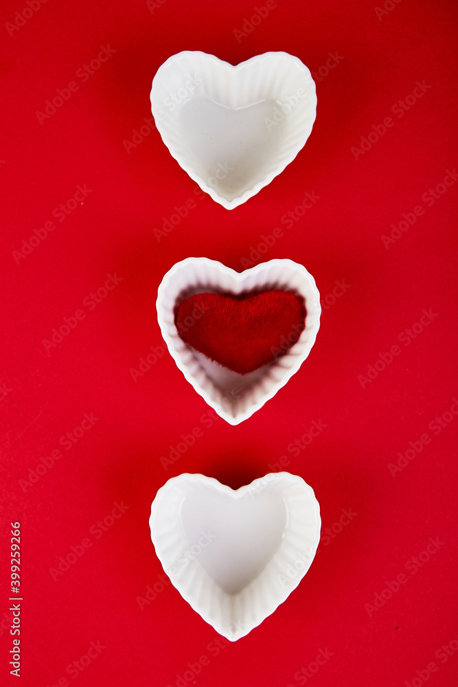 White ceramic hearts with red plush  hearts on red background. Flat lay composition. Romantic, St Valentines Day concept. Love. Copy space.