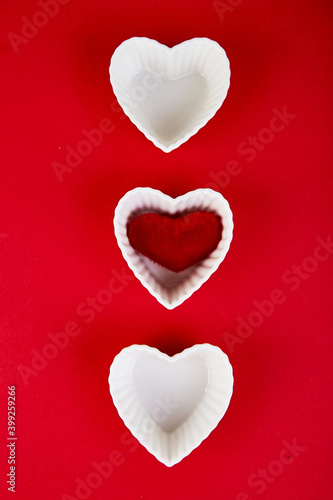 White ceramic hearts with red plush hearts on red background. Flat lay composition. Romantic, St Valentines Day concept. Love. Copy space.