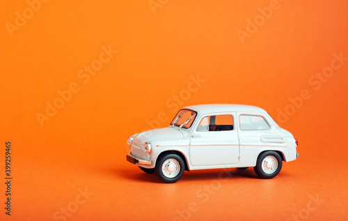 White car on colored background. Model white retro toy car on orange background. Miniature car with copyspace photo