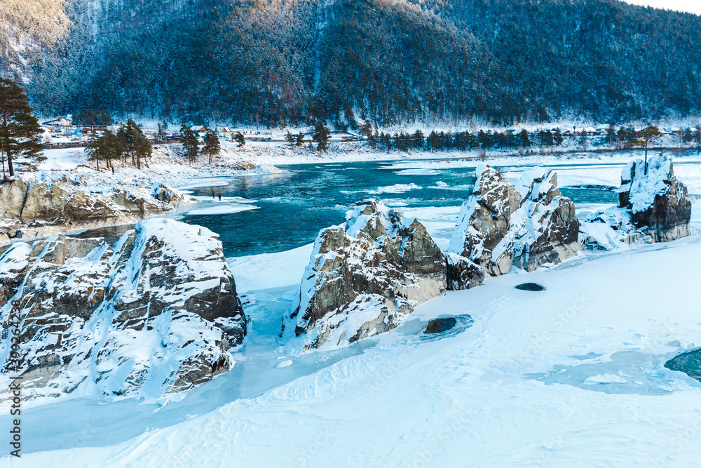 Winter landscape with rocks, stones and ice in the river. The trees and stones are covered with snow