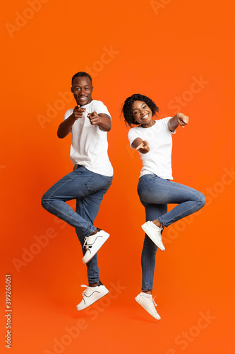 Emotional black couple posing on orange studio background