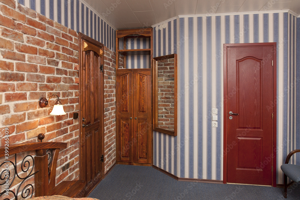 Bed in bedroom with wallpaper and brick wall and wooden cupboards and doors. Bed in bedroom with wallpaper and brick wall and wooden cupboards and doors.