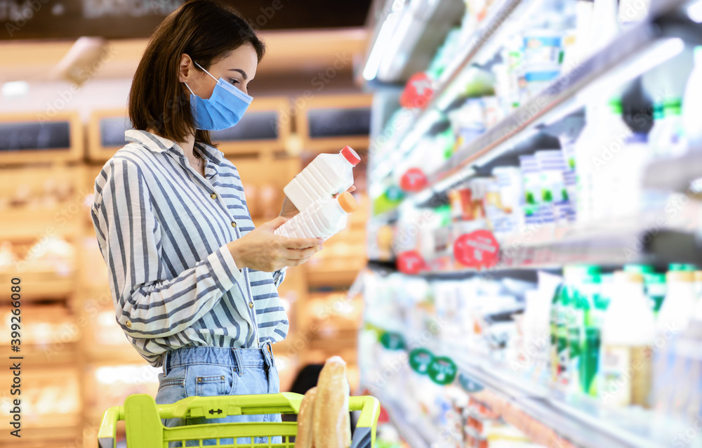 Woman in disposable mask shopping groceries, buying milk