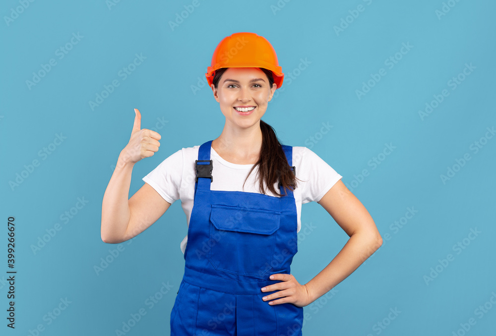 Portrait Of Young Handywoman Lady In Hardhat And Coveralls Showing Thumb Up Portrait Of Young Handywoman Lady In Hardhat And Coveralls Showing Thumb Up