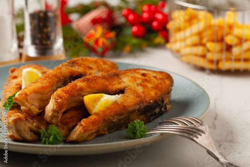 Fried carp in pieces, served on a gray plate. Marbled bright background.
