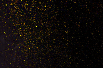 Golden falling glitter on the black background, festive overlay