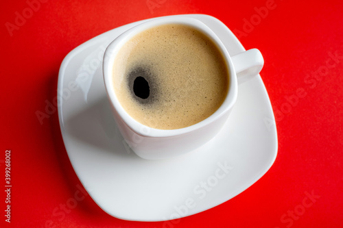 Coffee espresso in white cup. Coffee cup on red background closeup. Morning, breakfast, energy, coffee break concept. Top view