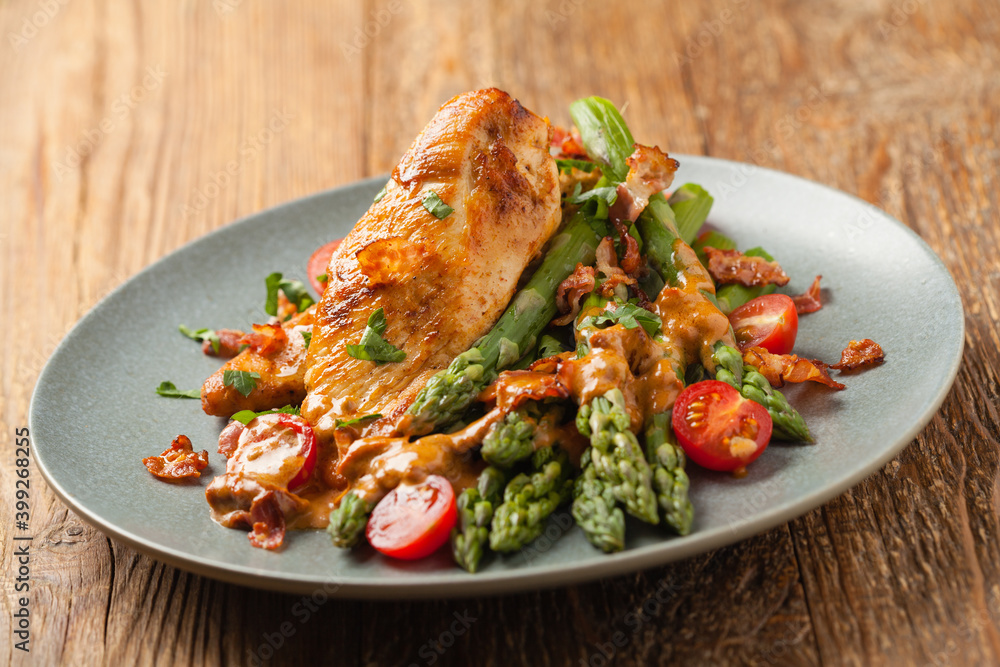 Roasted chicken breast, served on asparagus with tomato sauce, dried tomatoes. Front view. Roasted chicken breast, served on asparagus with tomato sauce, dried tomatoes. Front view.