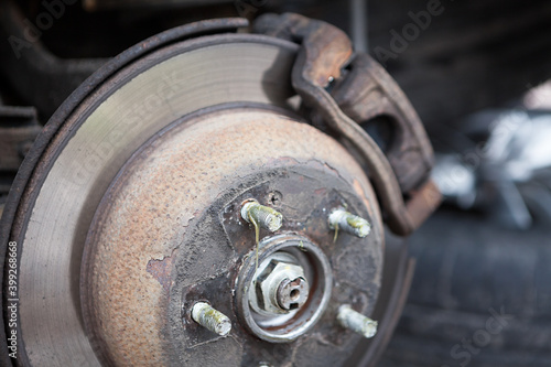 Old thin ventilated brake disk with used brake pads are ready for replacing, close up view