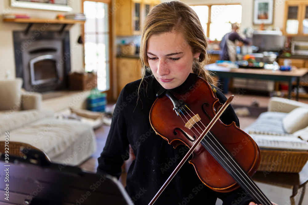 Teenage girl practicing violin at home