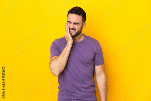 Young caucasian handsome man isolated on yellow background with toothache