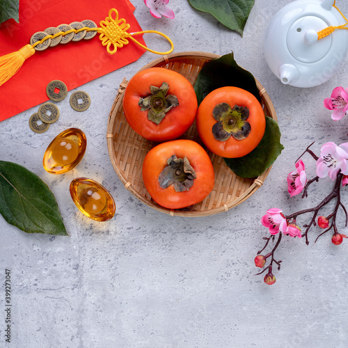 Top view of fresh sweet persimmons with leaves on gray table background for Chinese lunar new year
