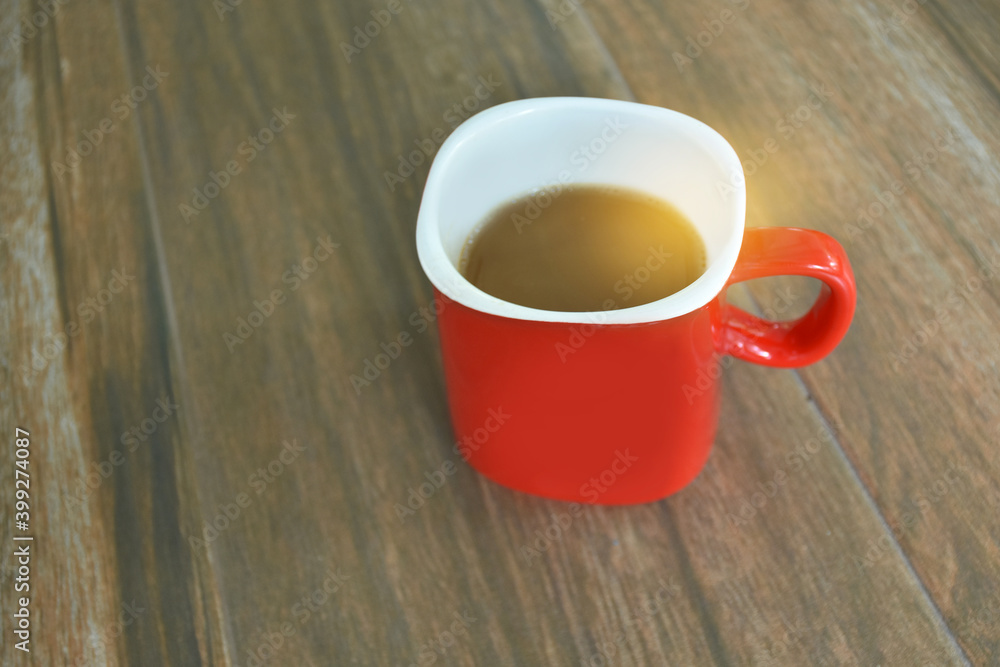 Obraz premium Red coffee cup on wooden table for people drinking in morning or relaxing time.
