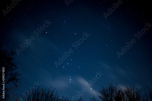 View of stars in a clear night sky with motion in clouds moving acroos the sky above