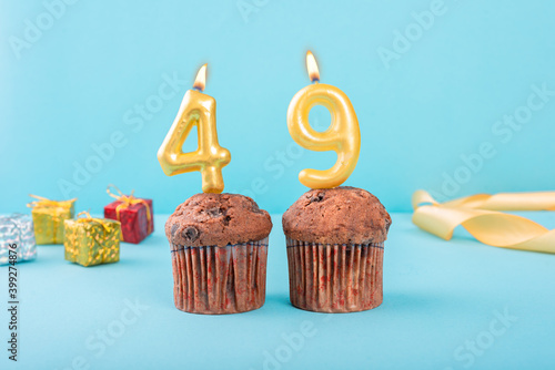 49 Number gold candle on a cupcake against a pastel blue background forty ninth year celebration photo